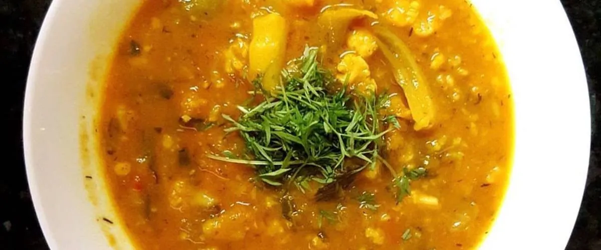 A bowl of chunky vegetable soup topped with fresh chopped herbs